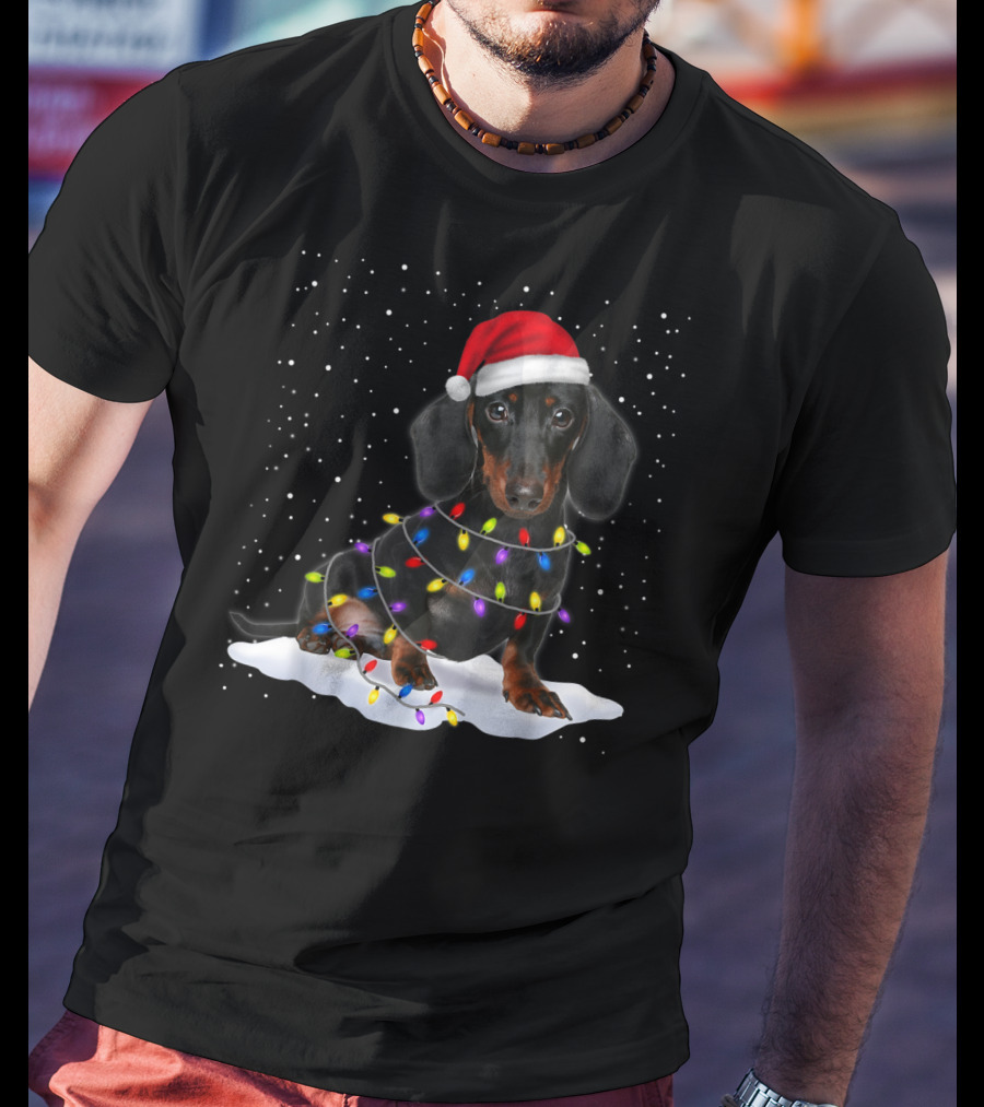 Dachshund Santa Hat Wrapped In Christmas Tree Lights In Snow With Falling Snowflakes T-Shirt