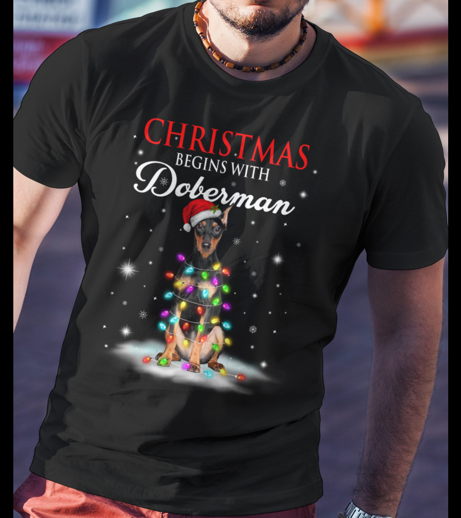Christmas Begins With Doberman Wrapped In Holiday Lights And Santa Hat Snowflakes T-Shirt