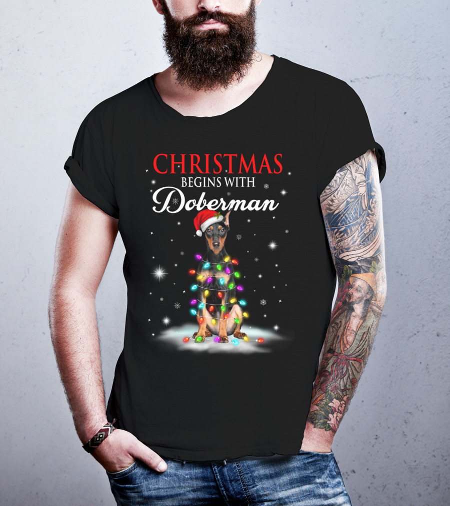 Christmas Begins With Doberman Wrapped In Holiday Lights And Santa Hat Snowflakes T-Shirt