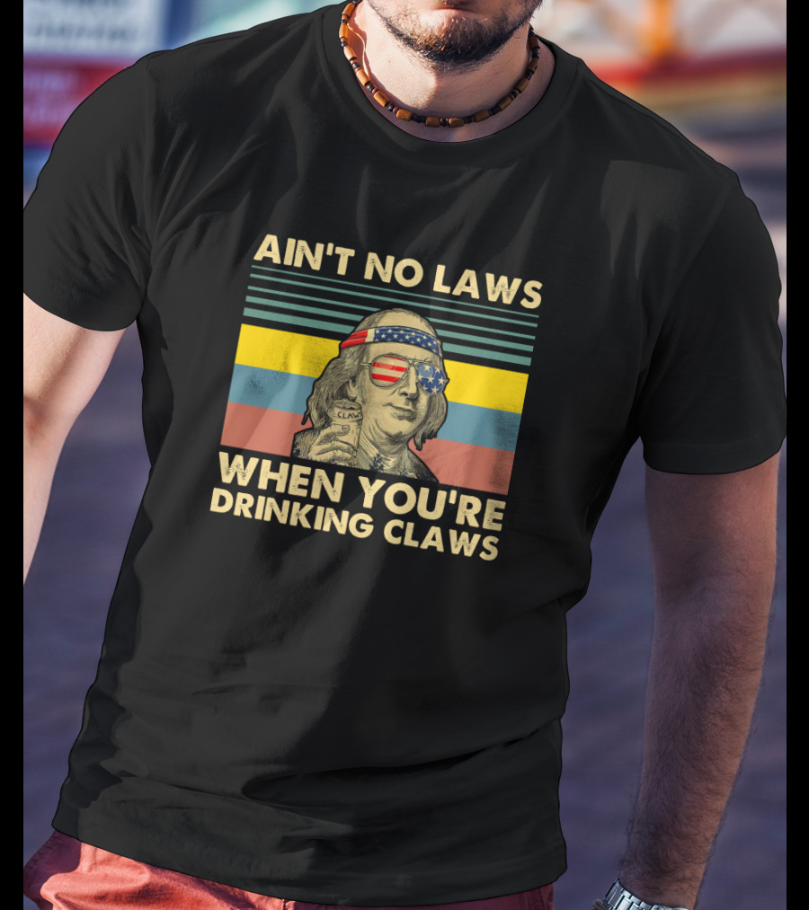 Ain't No Laws When You're Drinking Claws Vintage Benjamin Franklin With American Flag Glasses And Headband Can Of Clarified Beverage Stripes Background T-Shirt